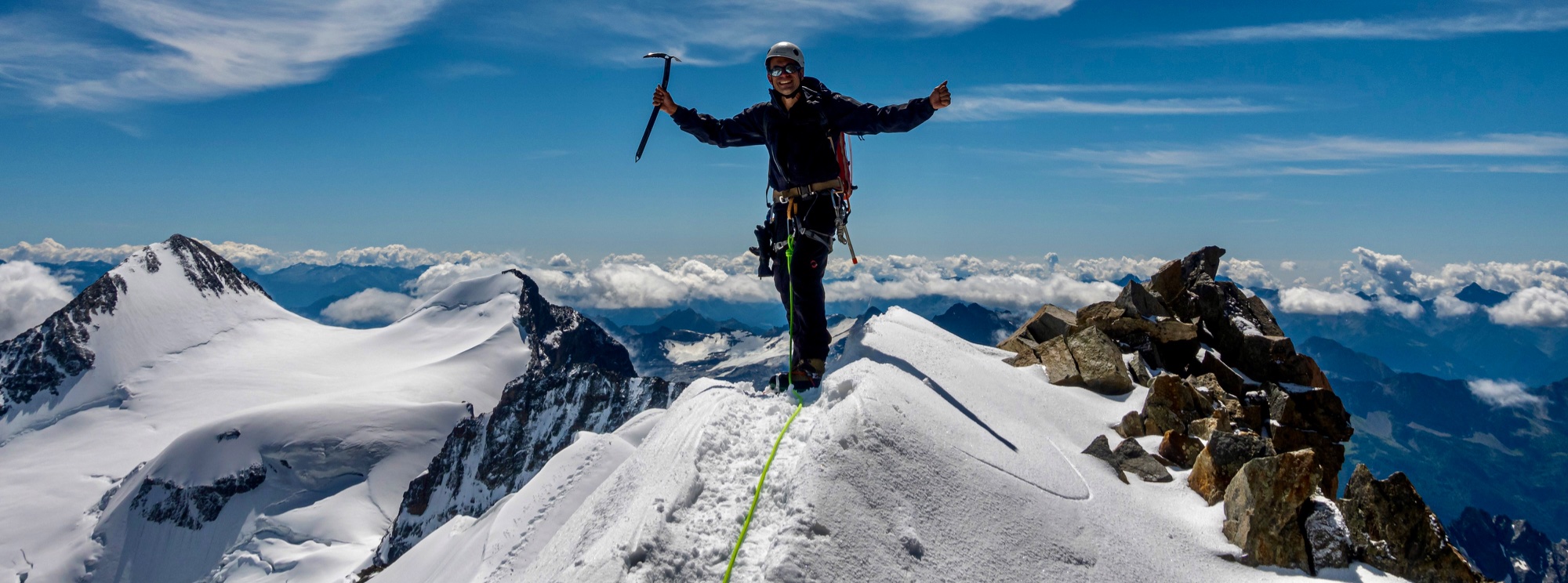 Mountaineer on summit ridge with Alpine panorama